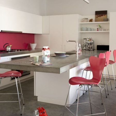 White open plan kitchen fitted units island breakfast bar unit with concrete worktop pink red bar stools by designer Arne Jacobseb Series 7 concrete floor real home L etc 02/2009 pub orig